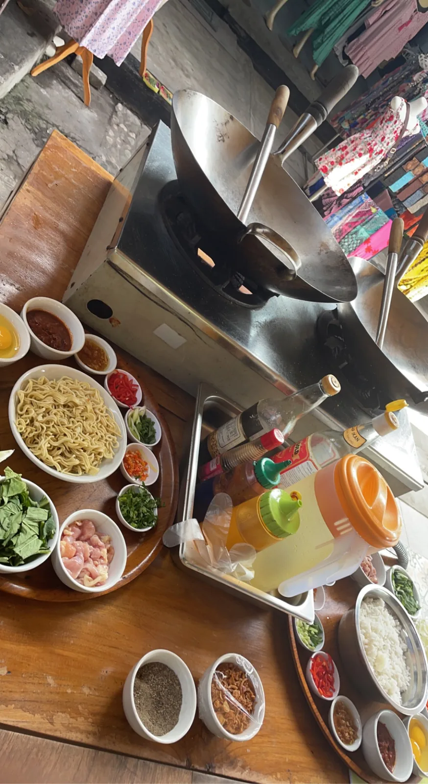 Cooking class station with a wok, bowls of noodles, spices and sauces