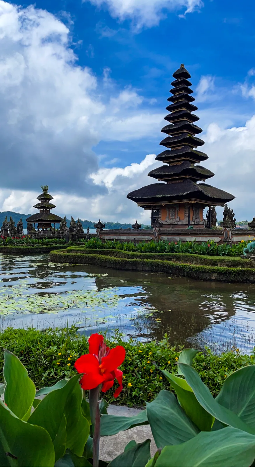 Ulun Danu Beratan behind red canna flowers, blue sky