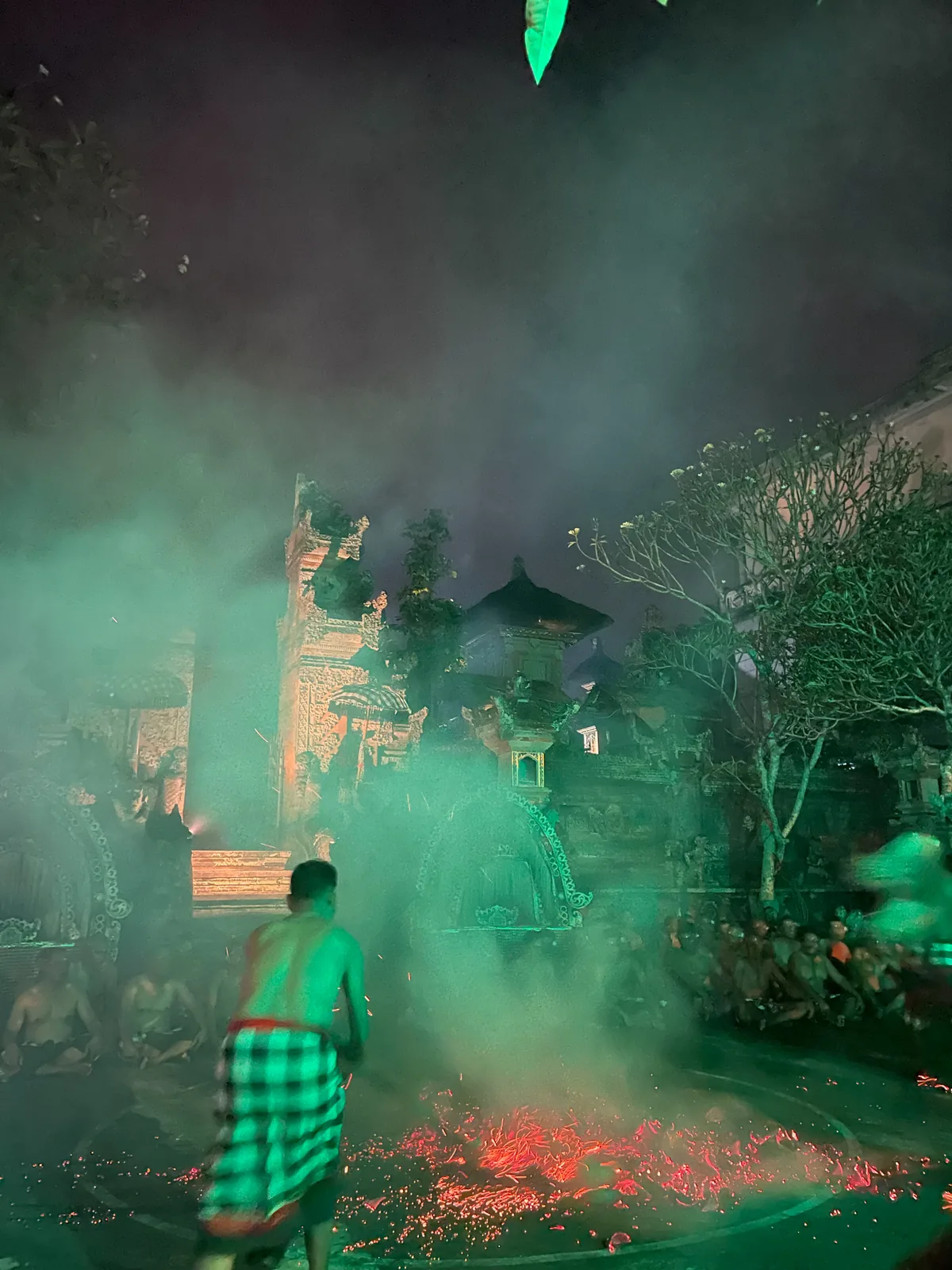 A fire dancer walking through glowing embers in green smoke