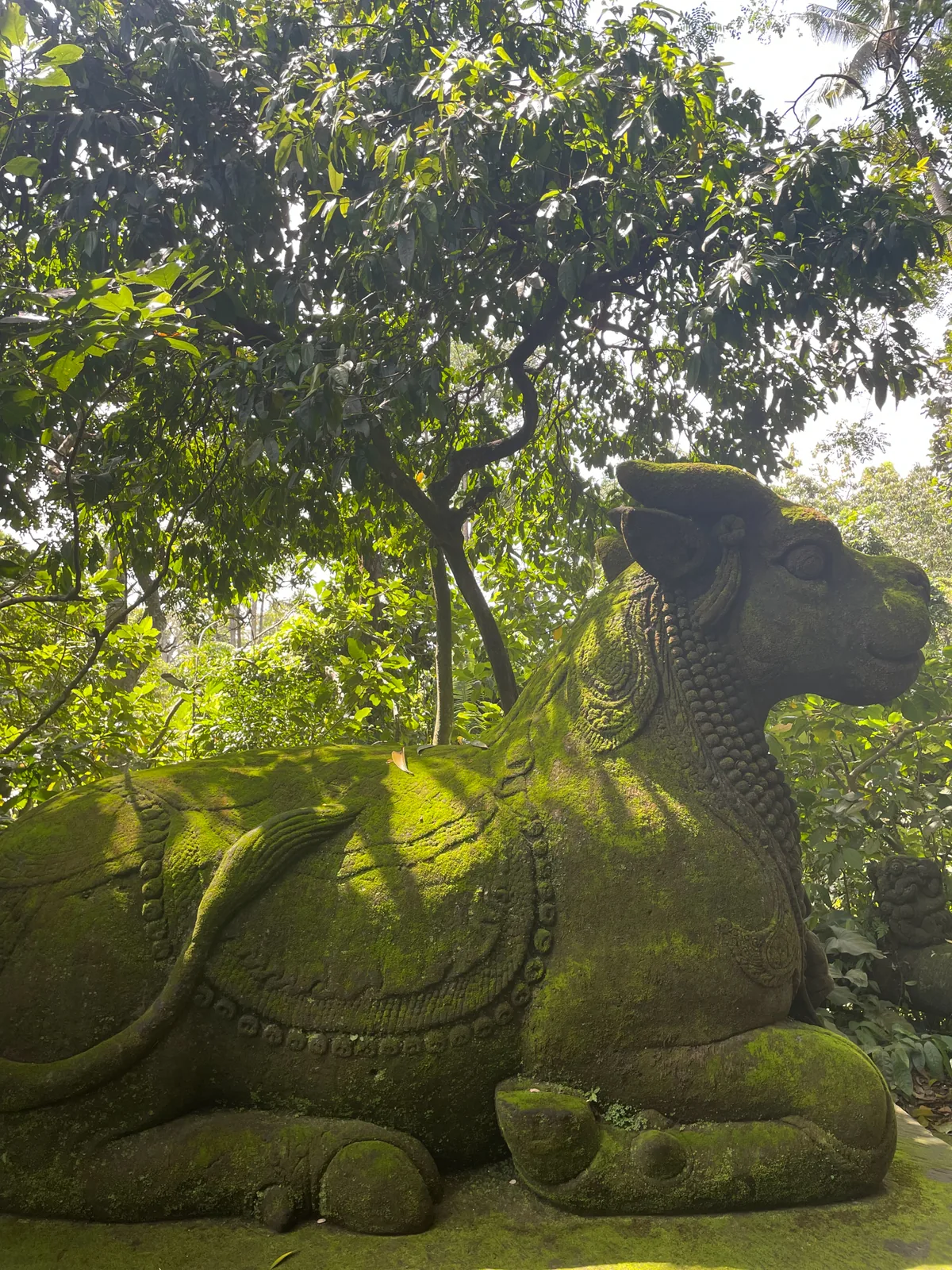 A moss-covered stone bull statue in the forest