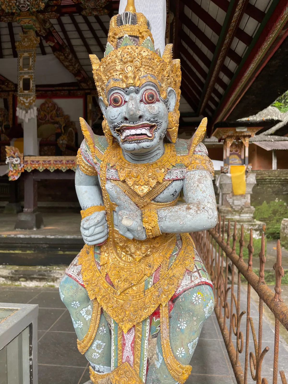 Painted gold and white guardian statue at a temple pavilion