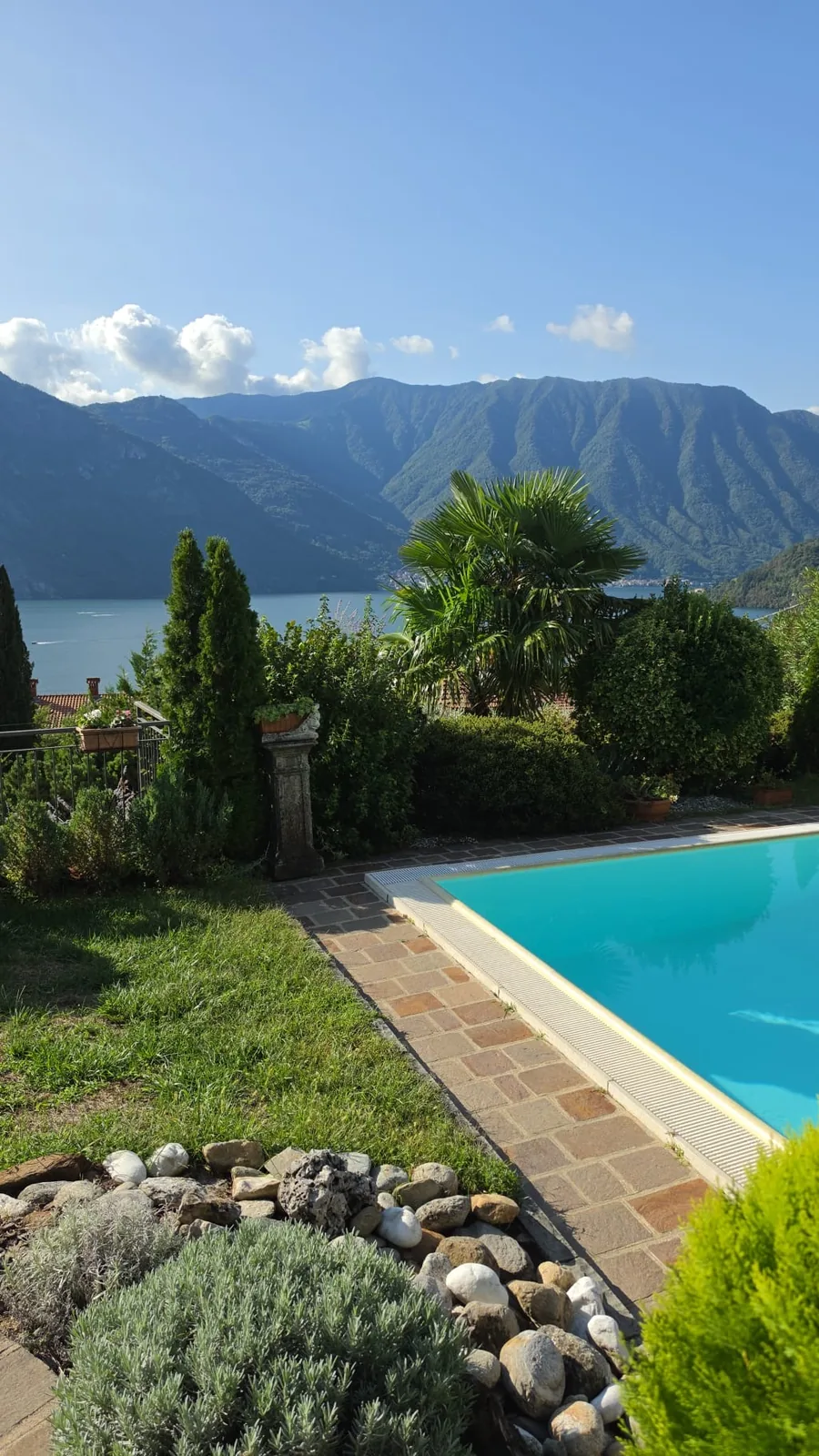 Villa pool on a sunny morning, turquoise water with the Alps and Lake Como behind, Tremezzo