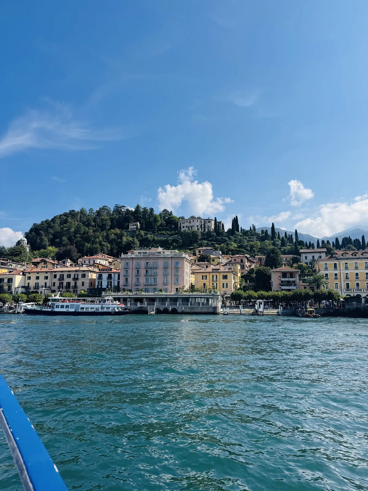 Bellagio waterfront approaching by ferry, pastel harbourfront hotels and hillside villas above the town
