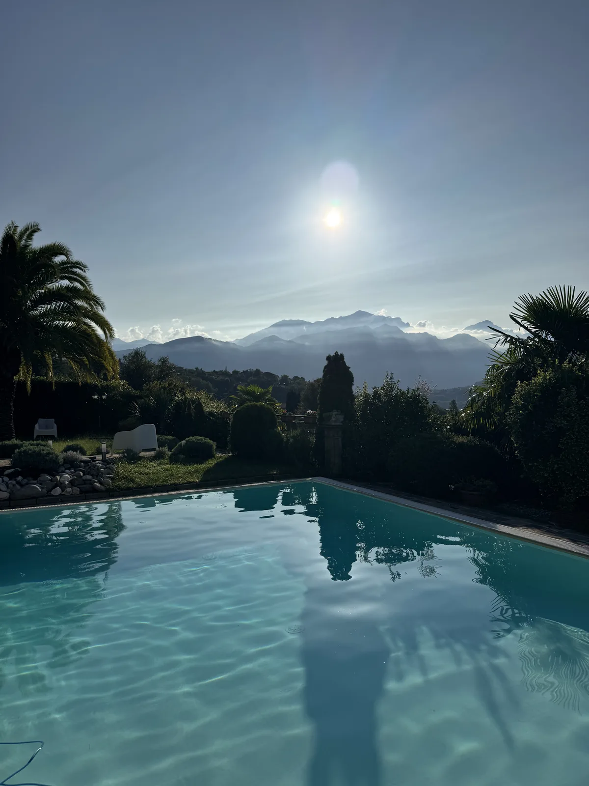 Villa pool terrace at dusk with the sun low over the Alps, Tremezzo, Lake Como