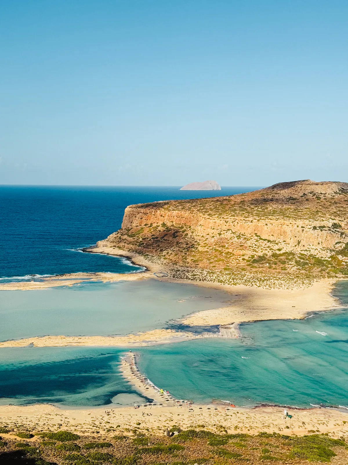 Balos lagoon from the path: sandbars curling through shallow turquoise water, Cape Tigani and an islet on the horizon
