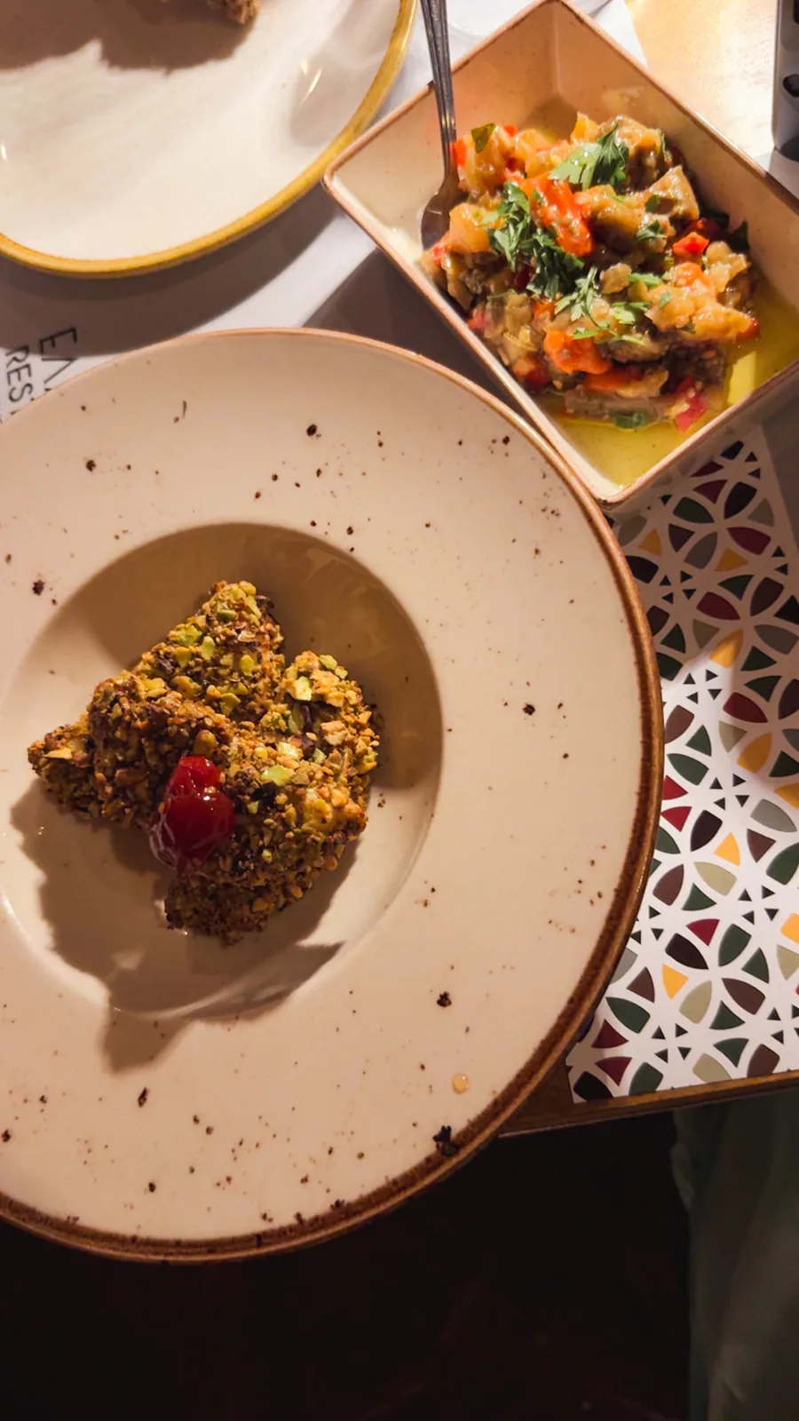 Dinner at Bohème, Chalidon street: a pistachio-crusted dish and roasted vegetables on patterned tile placemats