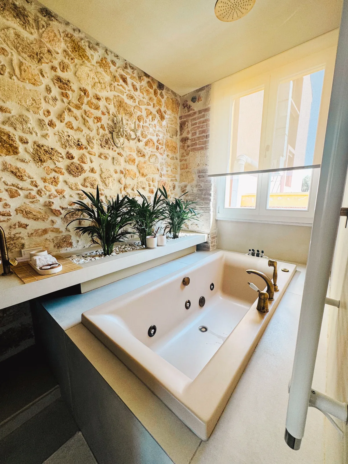 A sunken jacuzzi with brass taps against an old stone and brick wall