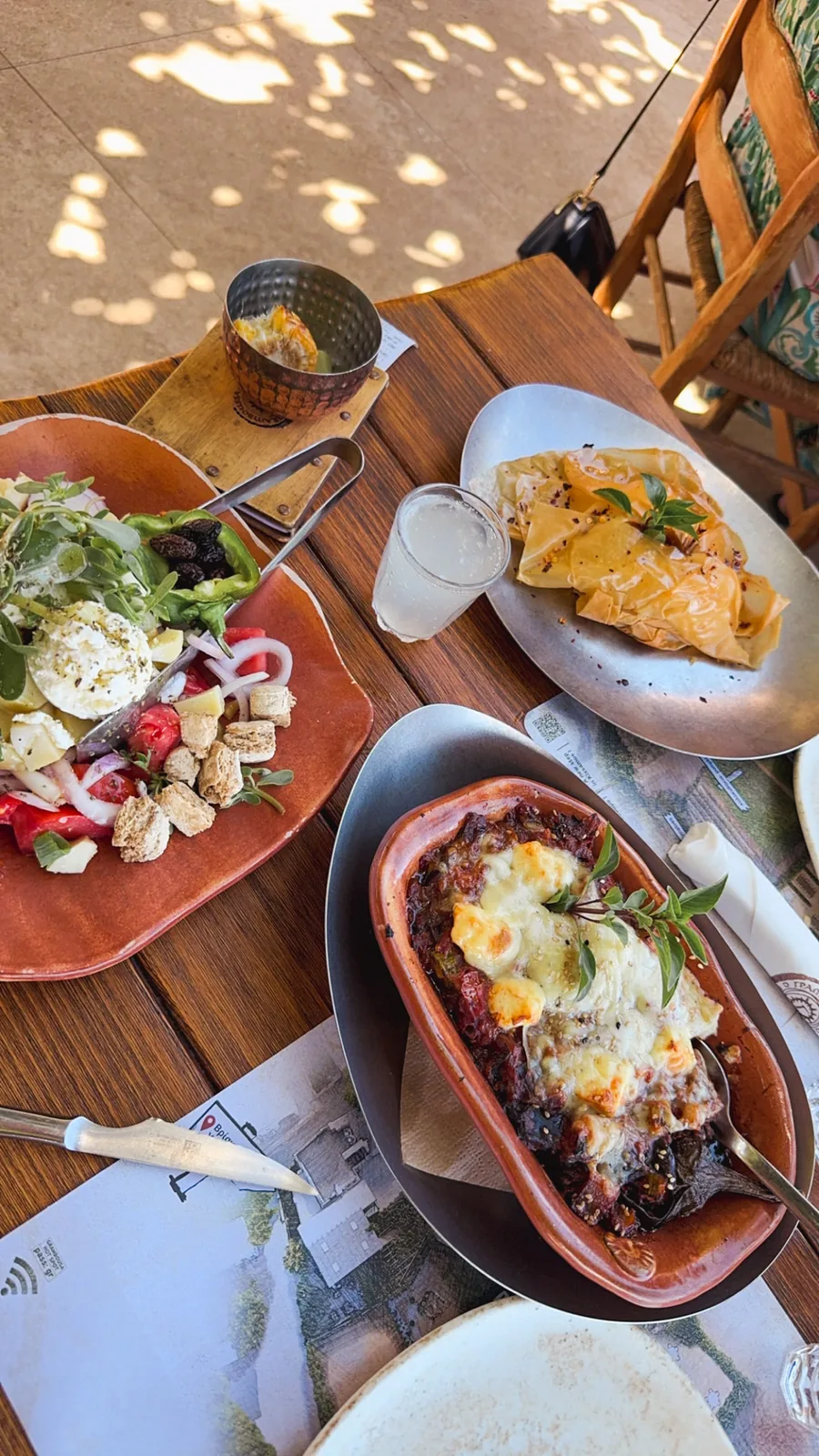 Lunch in Kaliviani: a Greek salad with feta and rusks beside a baked clay dish of melted cheese