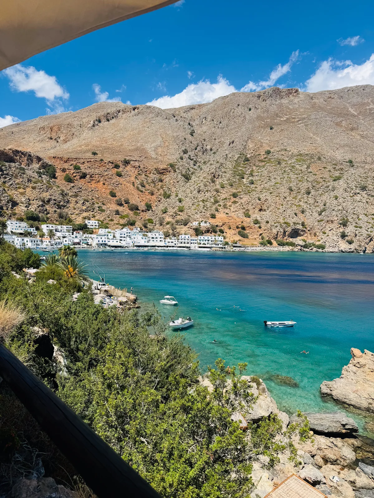 Loutro, a white village around a turquoise bay with a bare mountain behind and boats in the water