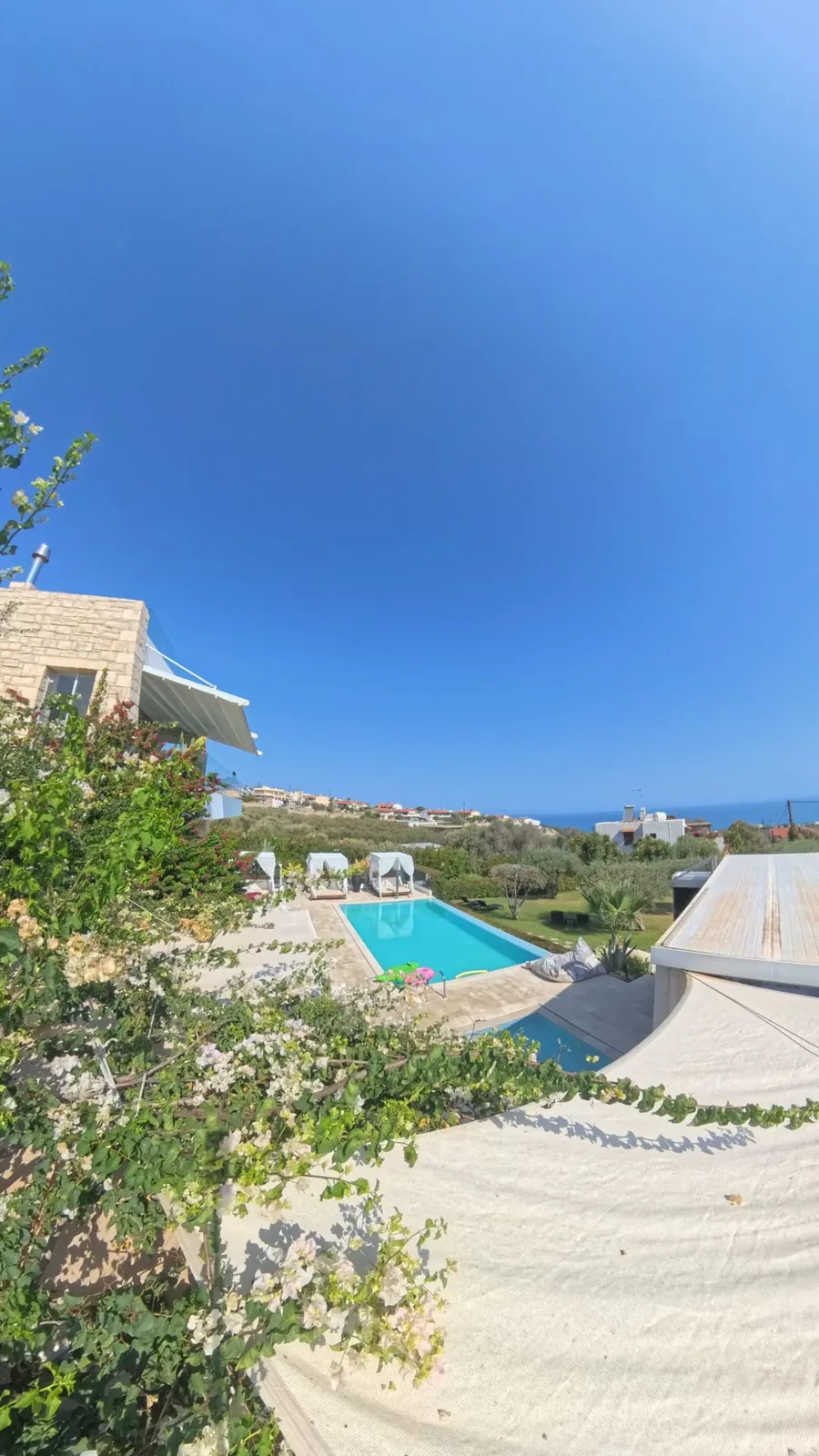 Stone villa, bougainvillea and the pool with white cabanas, the sea on the horizon