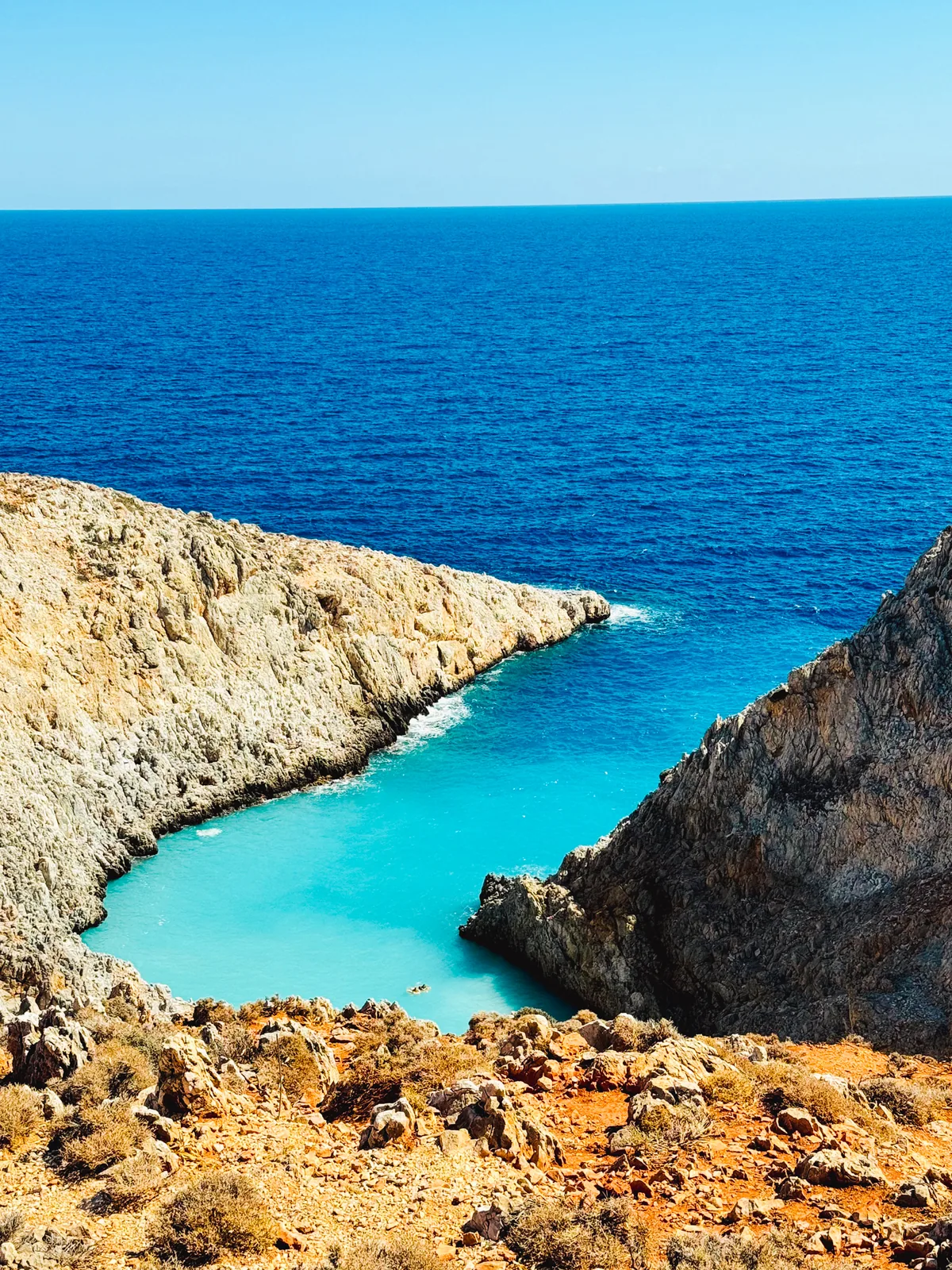 Seitan Limani from the cliff top, a narrow turquoise inlet between rock walls