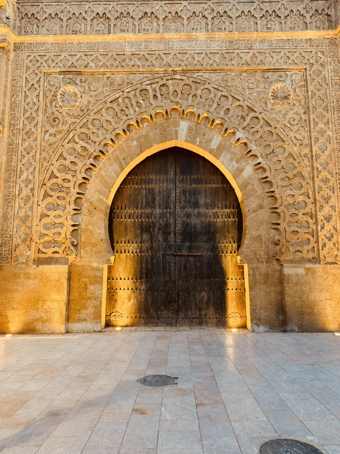 A monumental carved wooden gateway door in Fes glowing in low sun