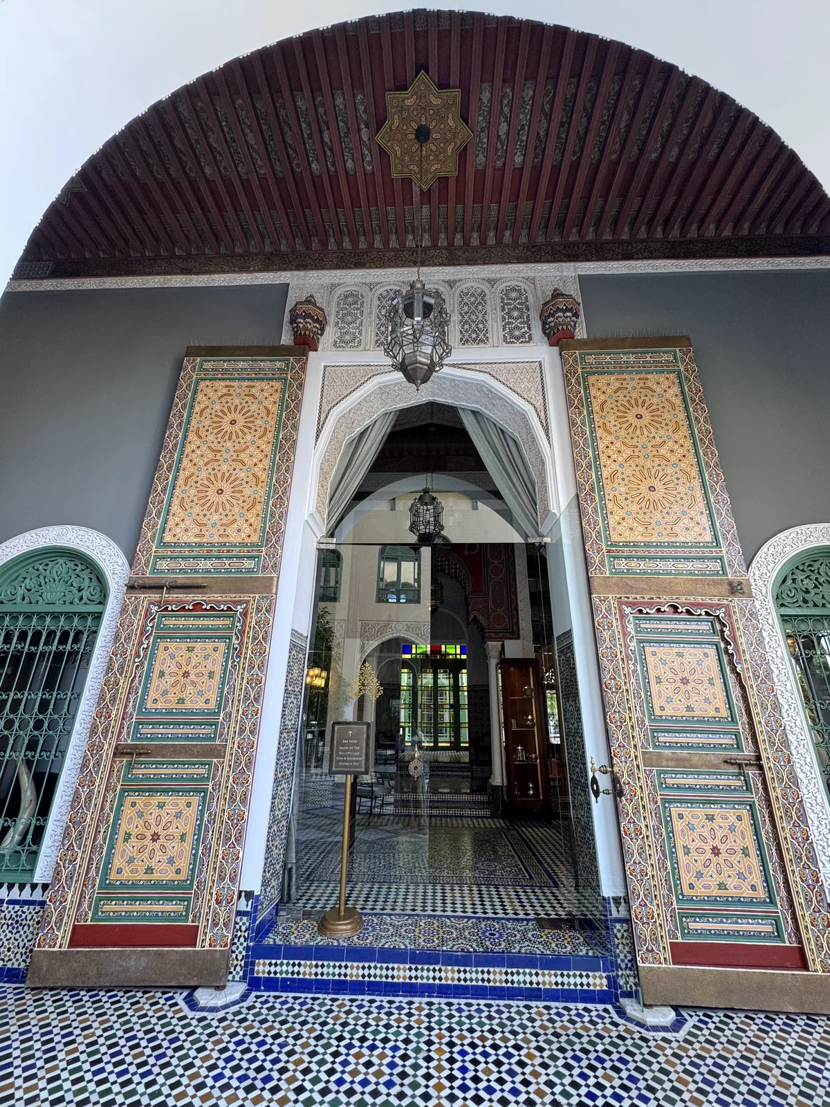 Carved painted doors opening into the tiled lobby of Palais Faraj