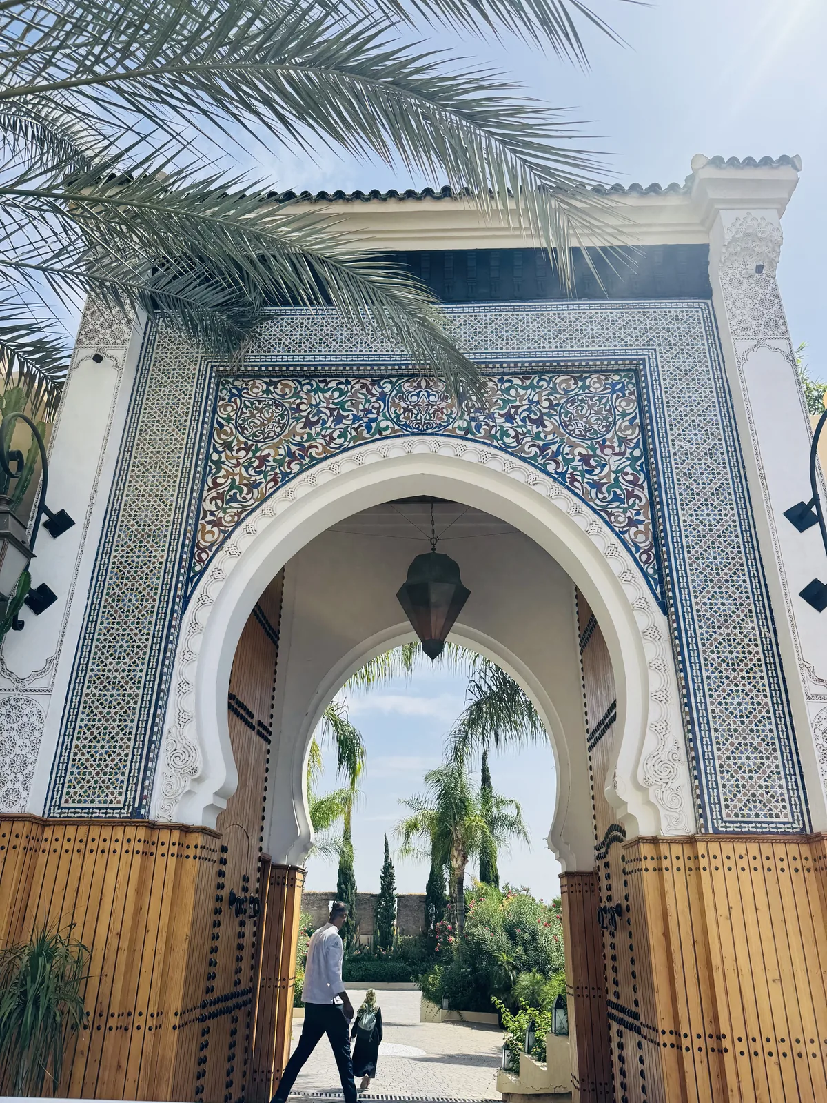The ornate zellige gate of Palais Faraj with a lantern hanging in the arch