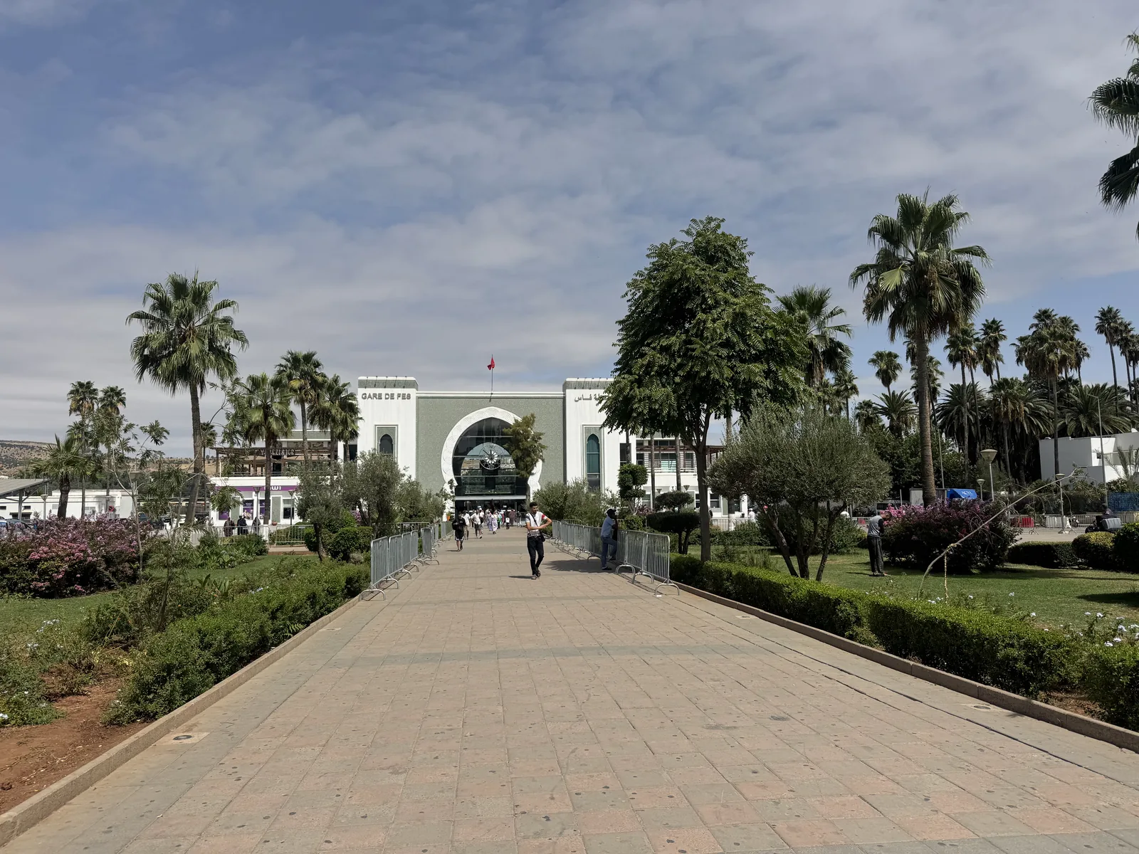 The white Moorish façade of Gare de Fes railway station, framed by palms
