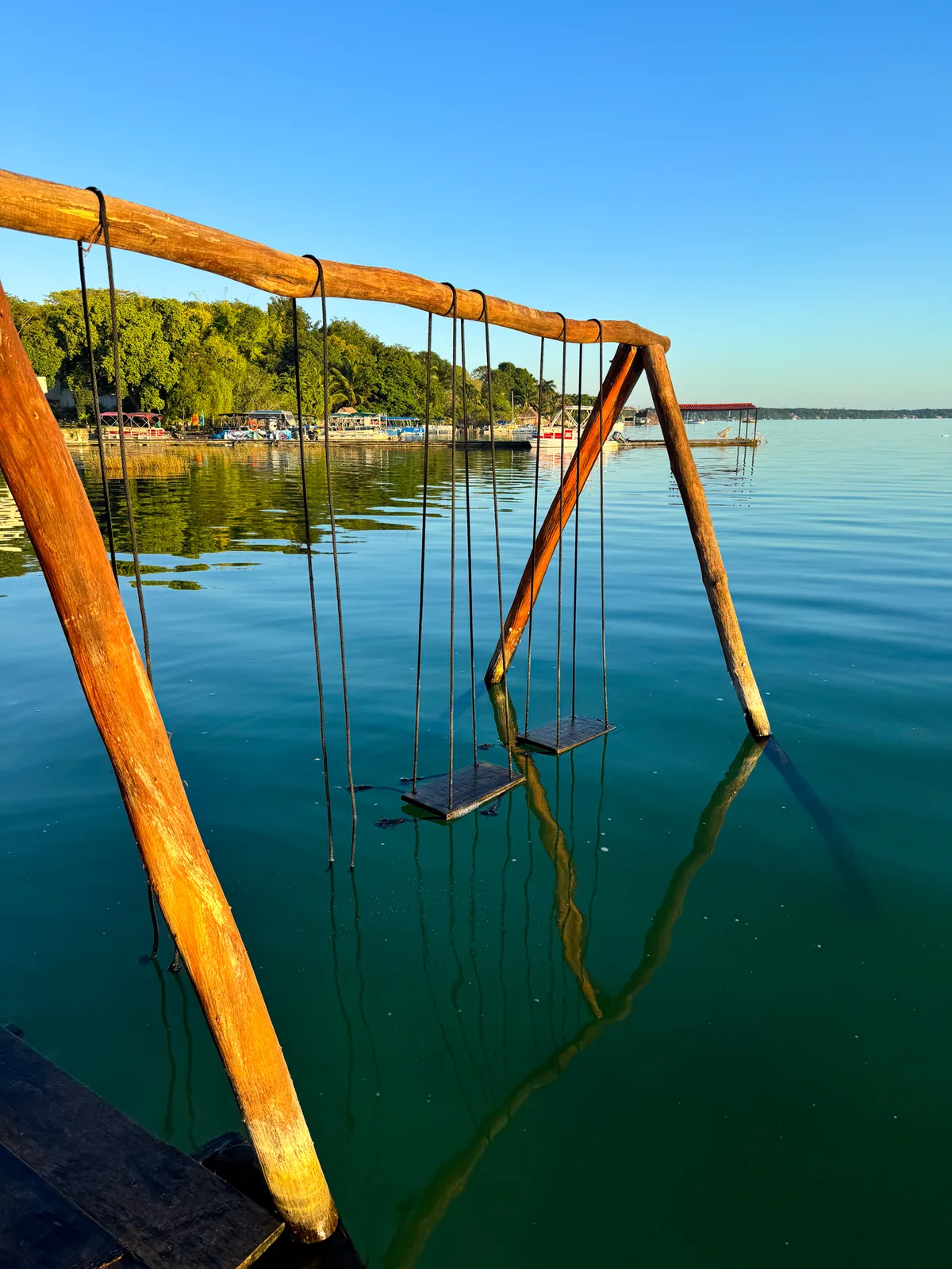 Wooden swings standing in the calm water of the Bacalar lagoon