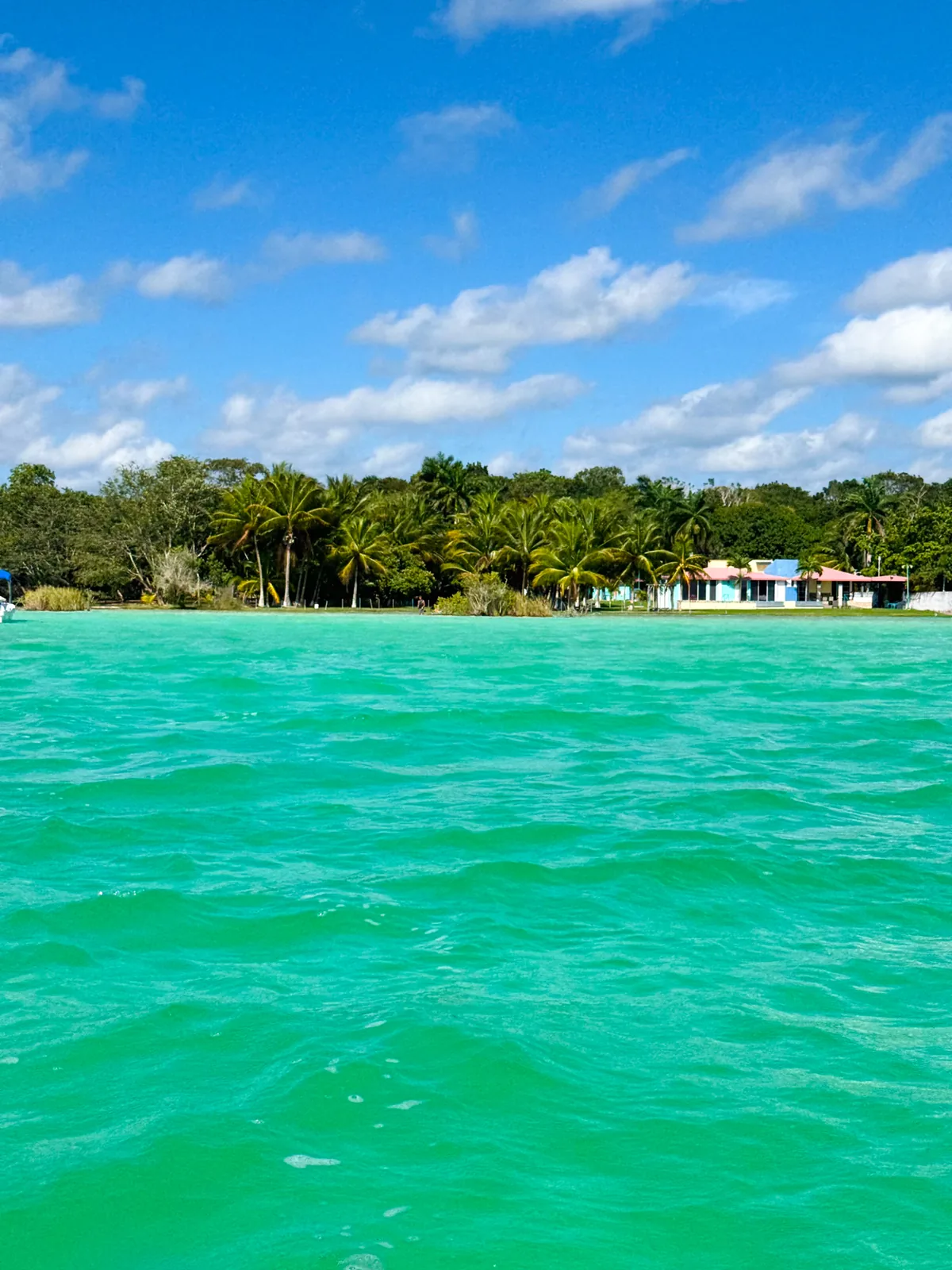 Open turquoise water and sky on the Bacalar lagoon, a house small on the far shore