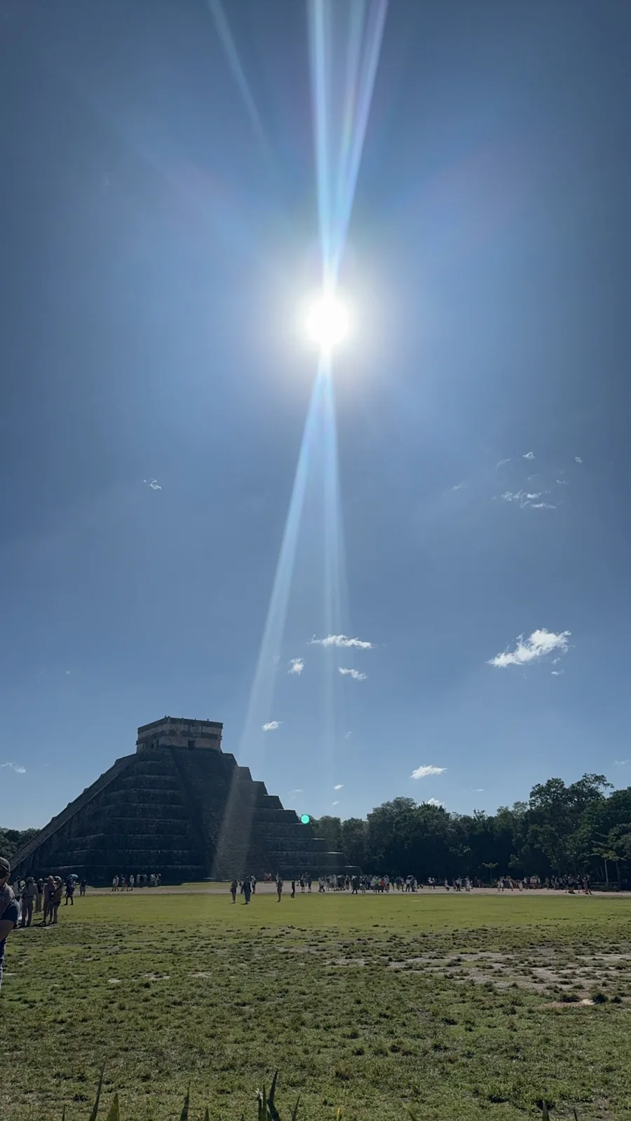El Castillo small on the horizon under a strong sun flare and a big sky
