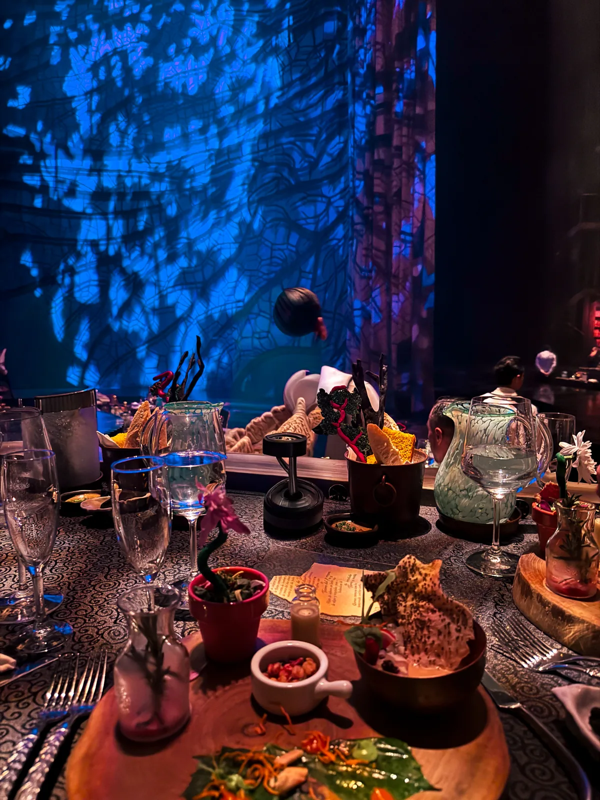 A dinner table set before the JOYÀ show, blue light projections behind