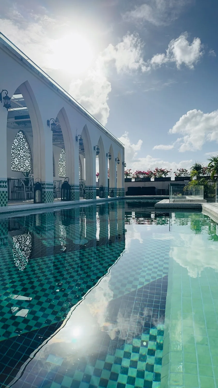 The green-tiled pool at Layla Tulum from the far end, arches reflected in the water