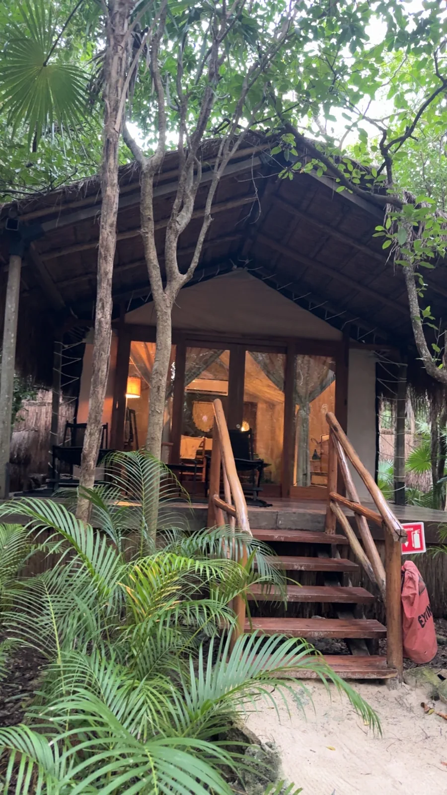 A thatched cabin on stilts in the jungle at Our Habitas, warm light glowing inside