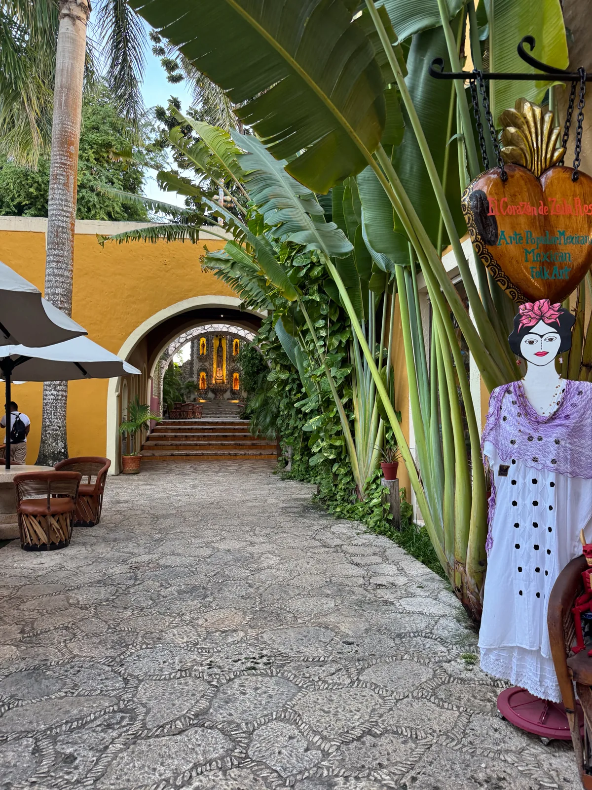 A yellow arched courtyard in Valladolid with a cobbled path and colourful folk-art decorations