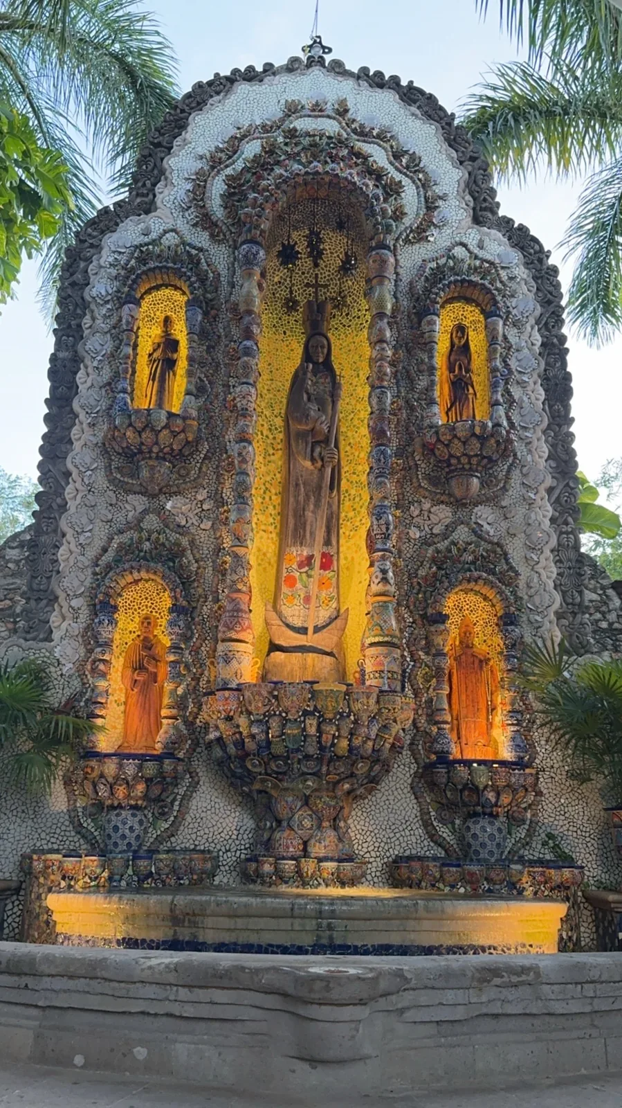 An ornate mosaic fountain with a statue of the Virgin in a lit niche, Valladolid