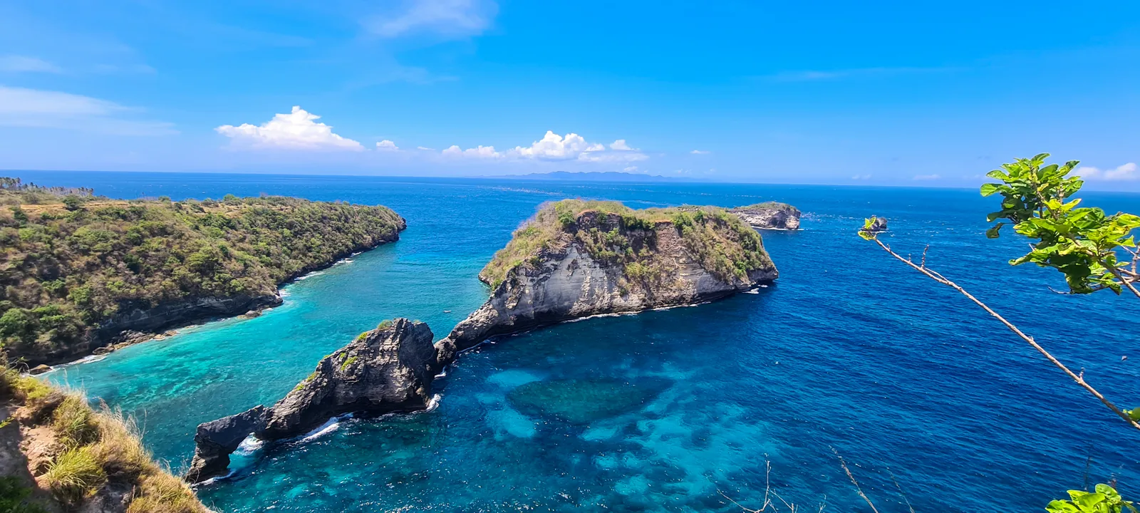 A panorama of islets and turquoise reef water from a clifftop on Nusa Penida.