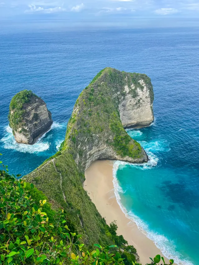 The Kelingking headland on Nusa Penida, shaped like a T-Rex, above a curve of white sand and turquoise sea